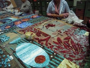 Los artesanos en Permono trabajan con pequeños pedazos de cristal para formar los diseños de lo que será el pavimento.