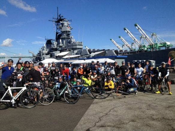 Ciclistas posando frente al USS Iowa.