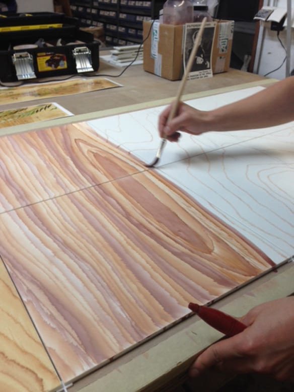 Artesanos pintan cuidadosamente un panel de madera. Foto: Mayer of Munich.